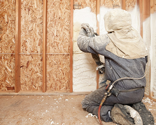 wall-insulation Technician spraying insulation between wall studs.